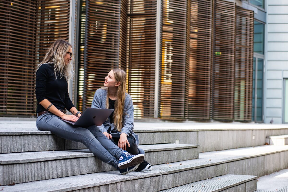 Twee vrouwen zitten op een trap en zijn met elkaar in gesprek